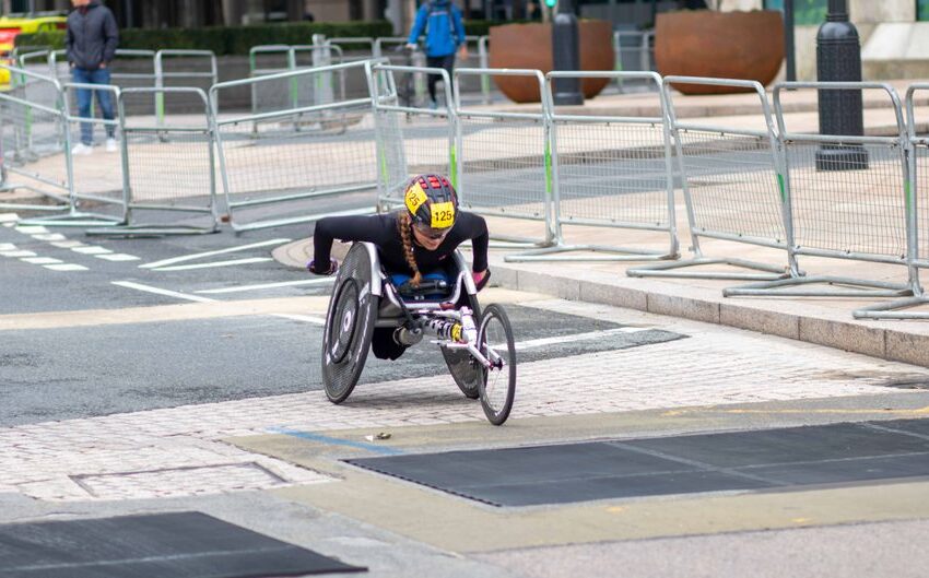 A dedicated athlete competes in a marathon using a racing wheelchair on city streets.