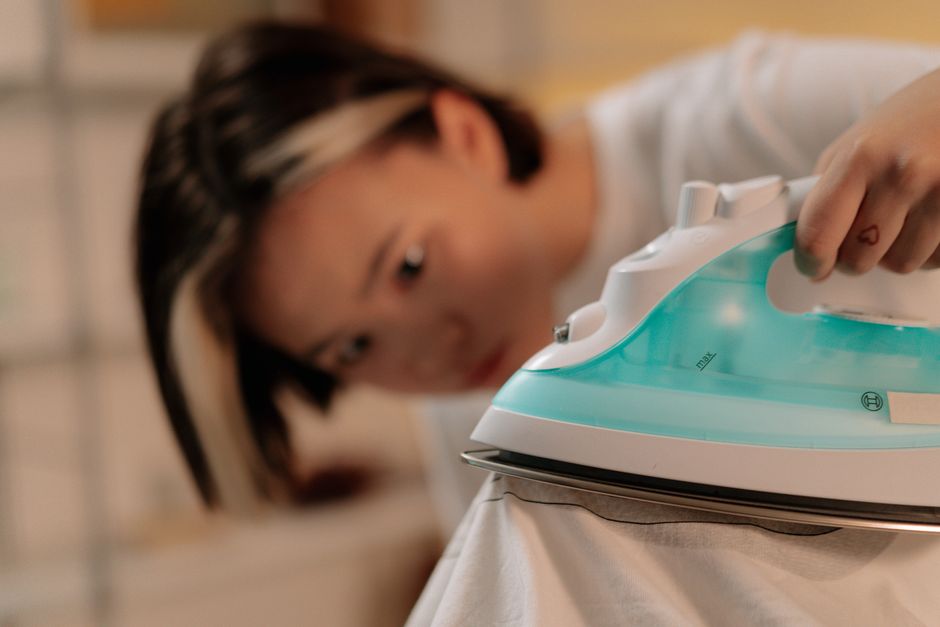 Focused woman ironing clothes at home, highlighting concentration and domestic tasks.
