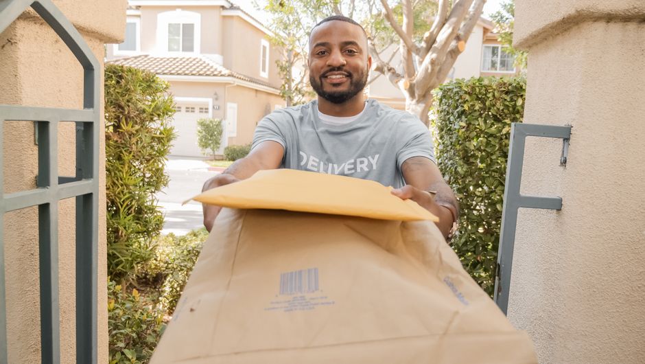 African American delivery man smiling while handing over parcels outdoors.