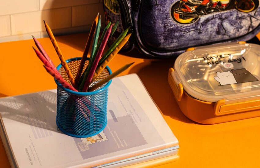 Vibrant pens, notebooks, lunch box, and backpack on a lively desk.