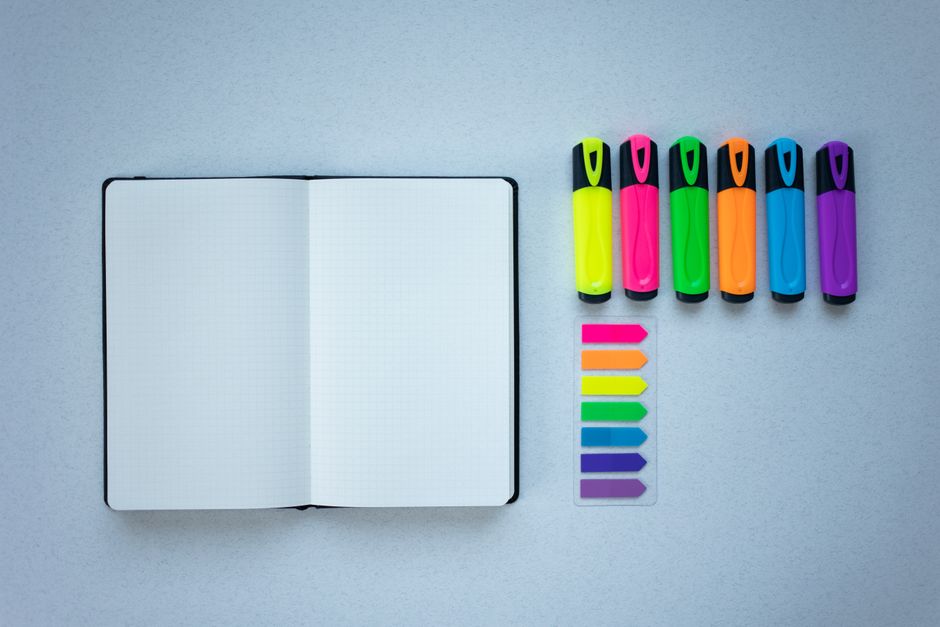 Flat lay of colorful highlighters and an open notebook, perfect for creative planning.