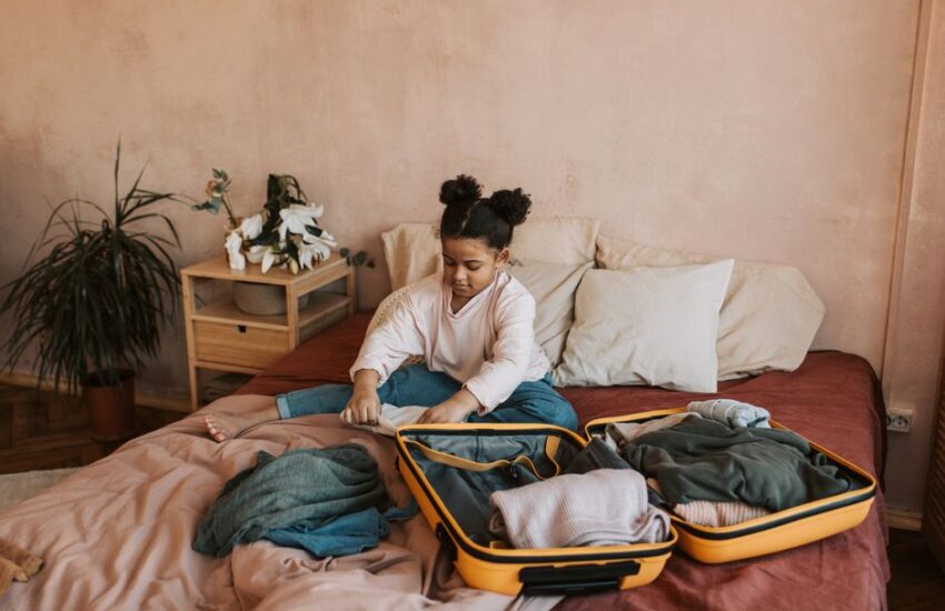 A young girl packing a suitcase on a bed in a cozy bedroom setting. Perfect for travel and family themes.