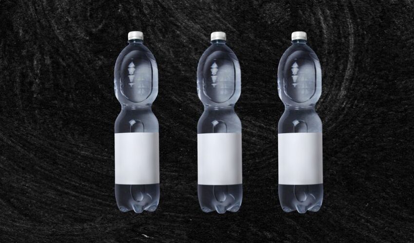 Plastic bottles of still spring water with white blank sticker placed against rough black background