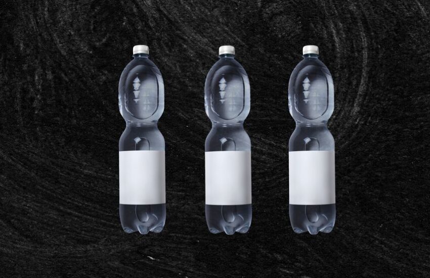 Plastic bottles of still spring water with white blank sticker placed against rough black background