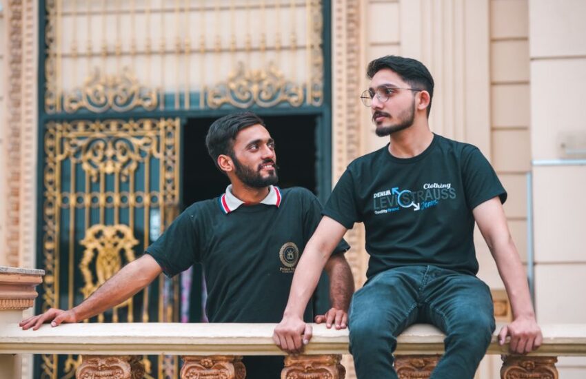 Two young men in casual outfits enjoying a moment on a decorative palace balcony.