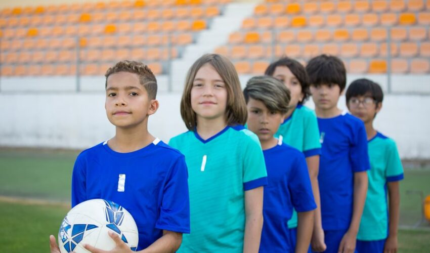 A diverse group of young soccer players in blue uniforms on a field in Portugal.