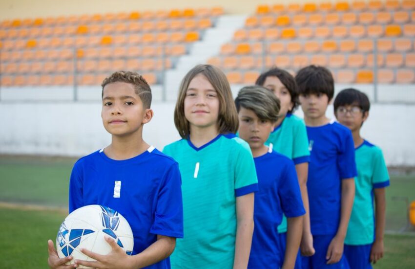 A diverse group of young soccer players in blue uniforms on a field in Portugal.