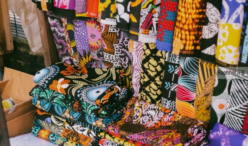 Vibrant African fabrics with various patterns displayed in a market stall.