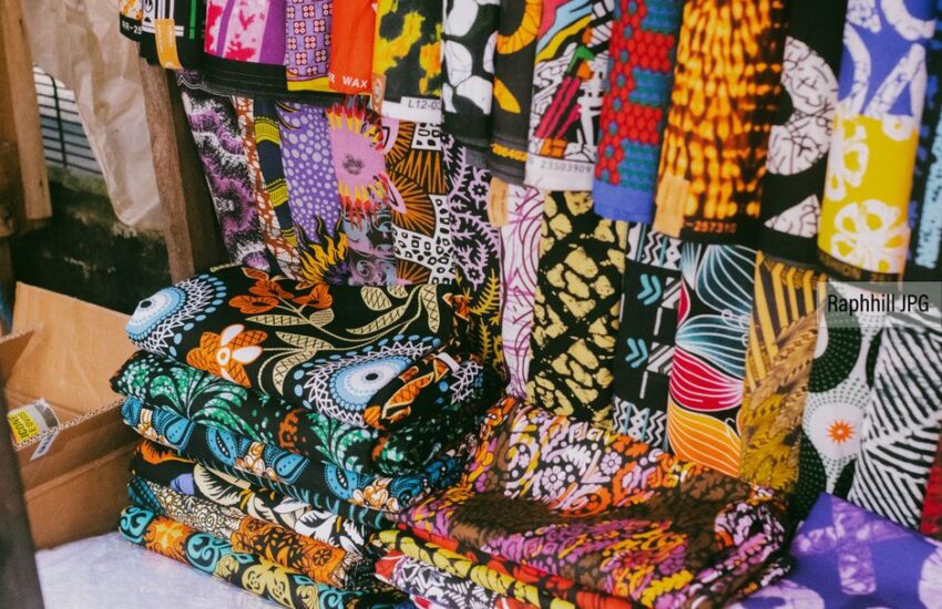 Vibrant African fabrics with various patterns displayed in a market stall.